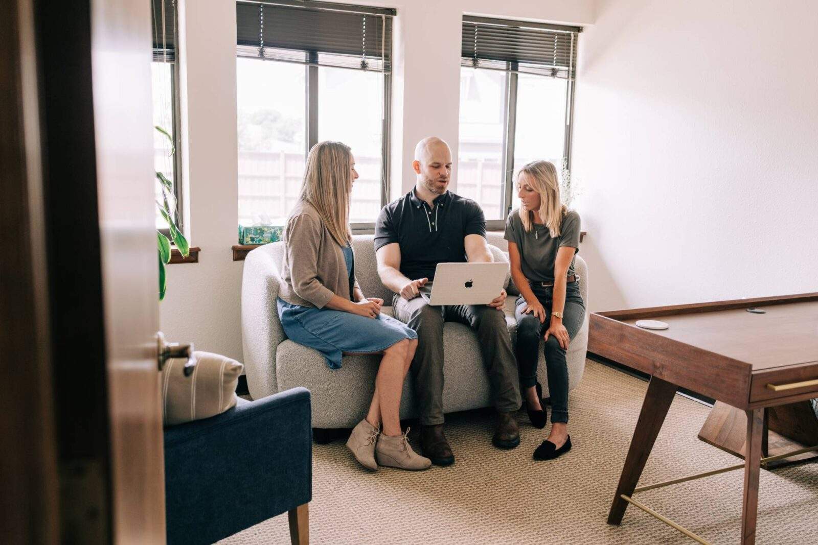 three Zephyr Behavioral Health & Wellness therapists talking while looking at a laptop while sitting on a couch in the office